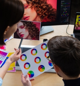 Graphistes analysant des nuanciers et un portrait pour des travaux de retouche photo et design graphique.